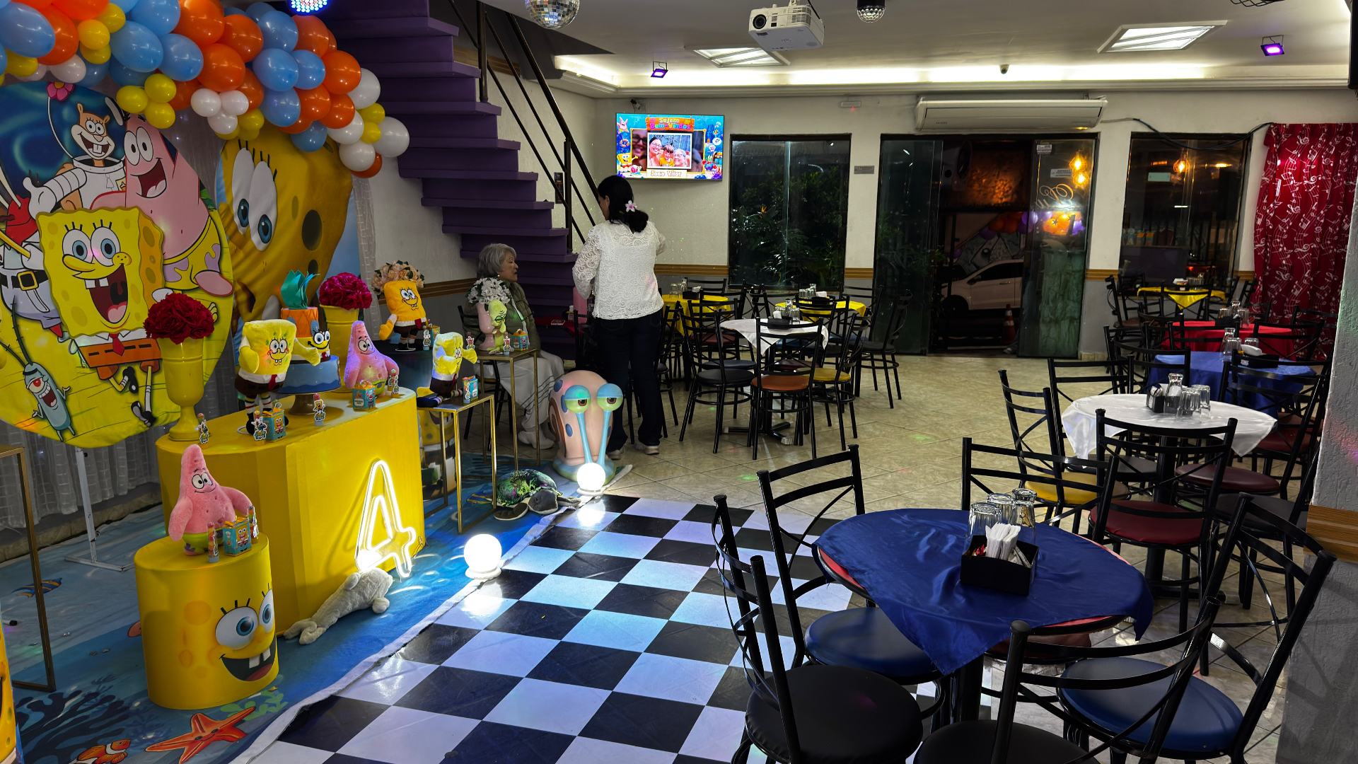 Salão principal do Castelo Mágico Buffet Infantil decorado com tema de festa, com mesas e piso quadriculado