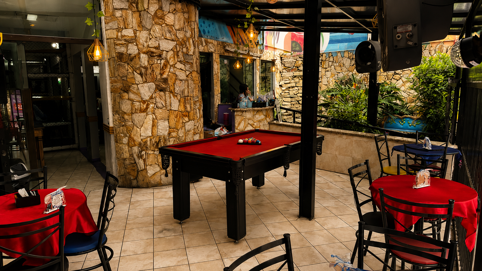Mesa de sinuca no lounge dos adultos do Castelo Mágico Buffet Infantil, com mesas vermelhas e pérgola com luminárias
