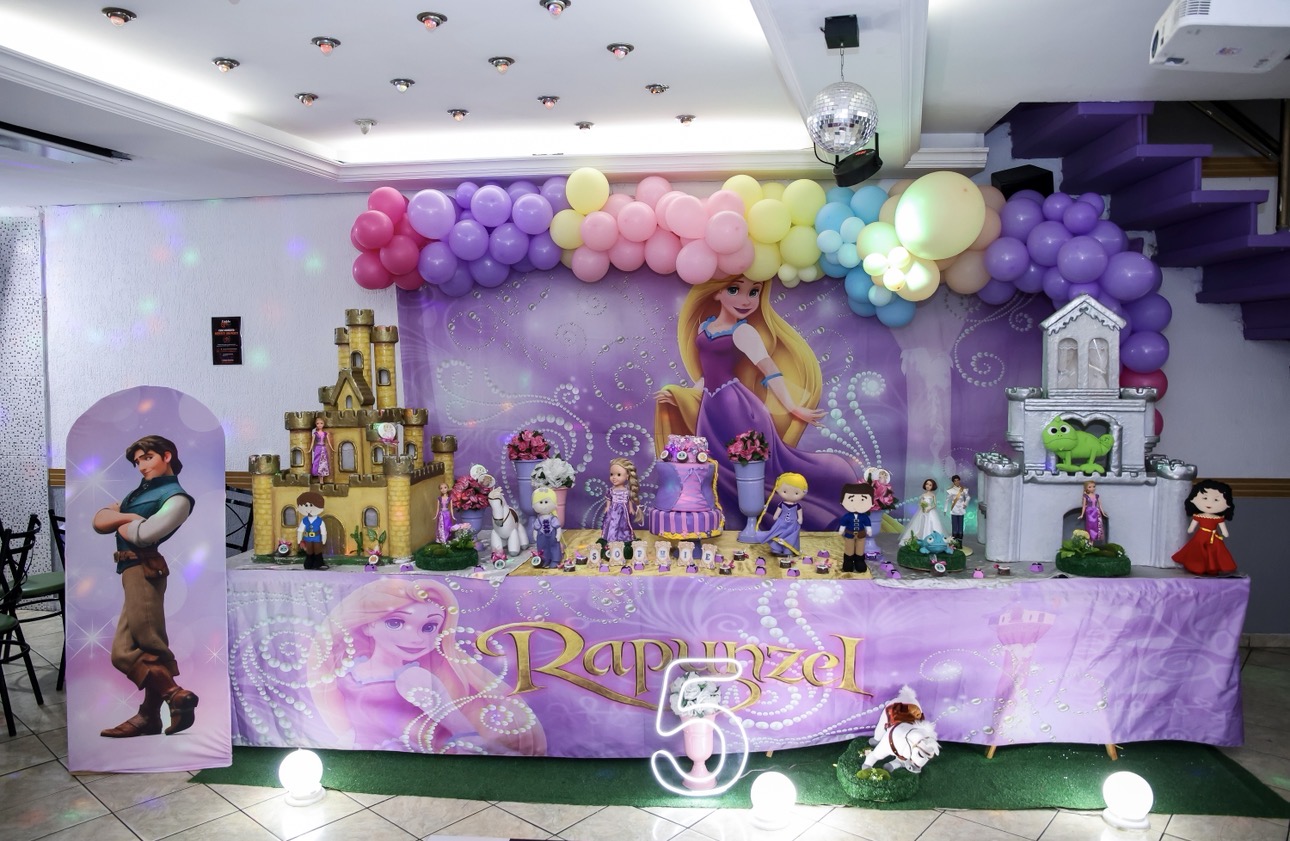 Mesa do bolo decorada no Castelo Mágico Buffet Infantil, com painel tema Rapunzel, castelos e arco de bolas