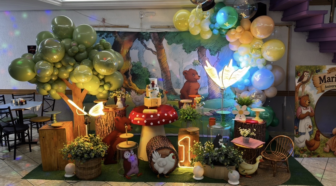 Decoração de festa no tema bosque no Castelo Mágico Buffet Infantil, com árvore de bolas, cogumelo decorativo e mesa do bolo