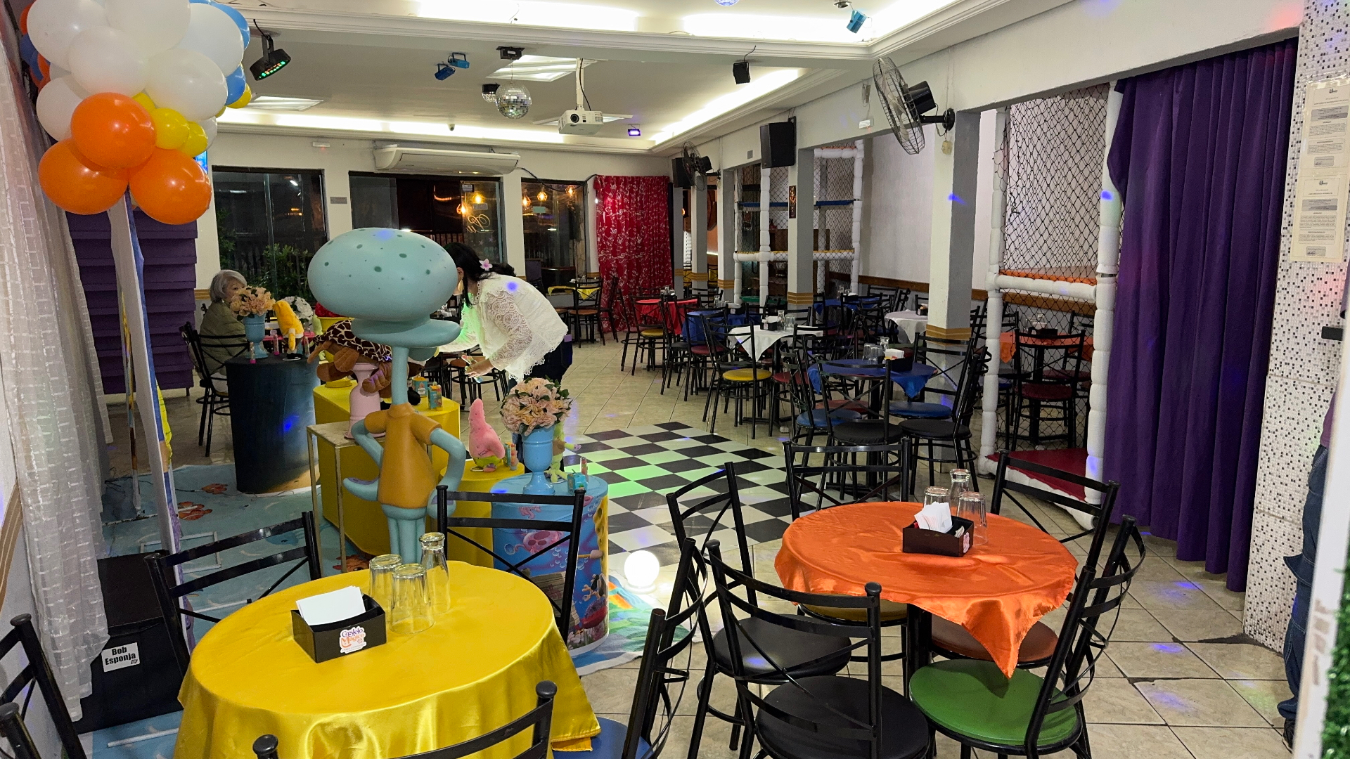 Cantinho decorado do salão principal do Castelo Mágico Buffet Infantil, com mesas preparadas para os convidados